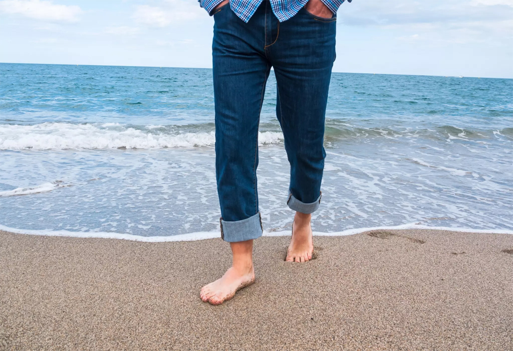 穿着牛仔裤的男人在海边散步